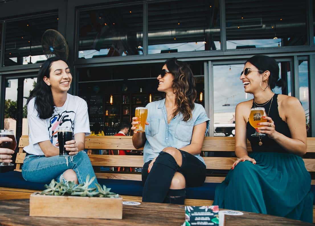 three women sitting on bench drinking The Best Belgian Beers